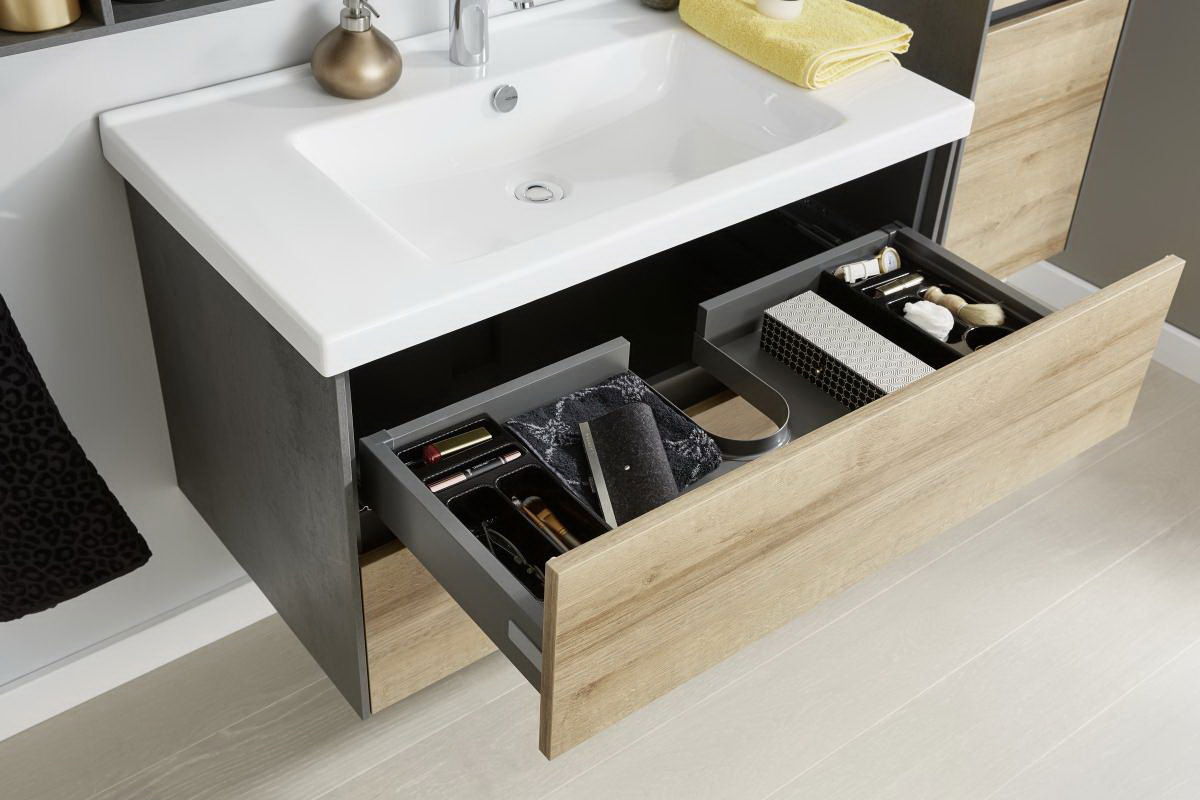 Badezimmerschrank mit Waschbecken und offenen Schubladen, gefüllt mit Pflegeprodukten, aus der Vogelperspektive