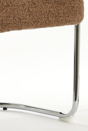 Nahaufnahme eines Armlehnstuhls mit braunem Stoffbezug und verchromtem Metallgestell, seitliche Perspektive.