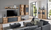 Modernes Wohnzimmer mit Wohnwand in Holzoptik und anthrazitfarbenen Fronten: TV-Lowboard, Wandregal, Hängeschränke mit Glasvitrine und Sideboard, aufgenommen aus schräger Frontperspektive.