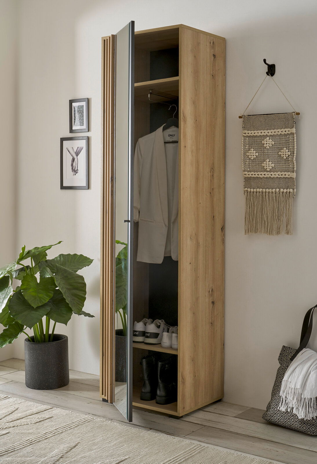 Schmaler Garderobenschrank aus Holz mit geöffneter Spiegeltür, zeigt Innenraum mit Kleiderstange und Schuhablage, seitliche Perspektive.