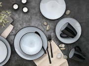 Vogelperspektive auf ein stilvolles 16-teiliges Kombiservice-Set mit grauen Tellern und Schalen sowie schwarzen Tassen auf einem dunklen Untergrund, dekoriert mit Steinen und Kerzen.