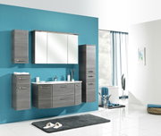 Modernes Badmöbel-Set in grauer Holzoptik mit Waschtisch-Unterschrank, Spiegelschrank und zwei Hochschränken an türkisfarbener Wand, frontal leicht schräg von vorn fotografiert.