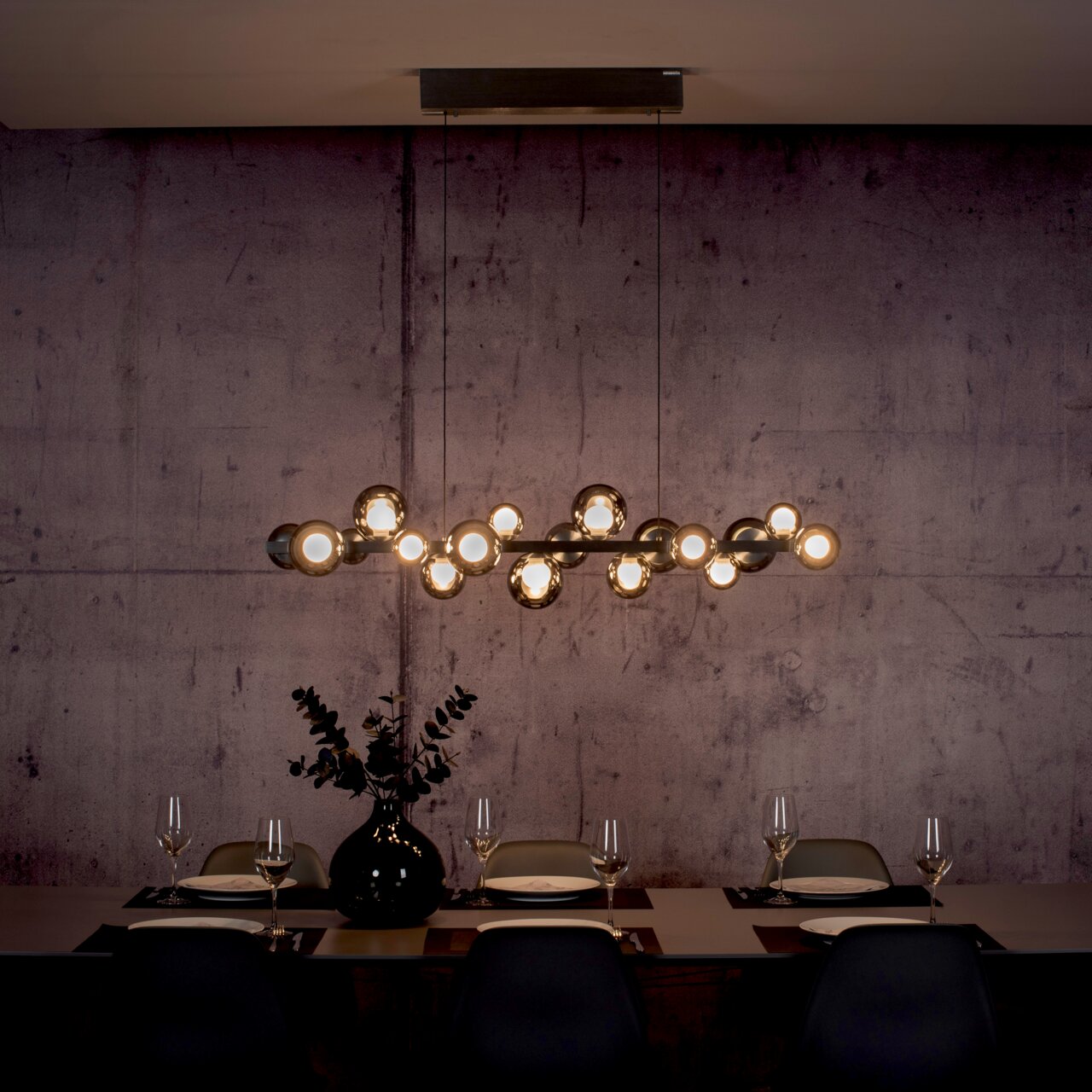 Moderne LED-Pendelleuchte über einem stilvoll gedeckten Esstisch, seitliche Perspektive