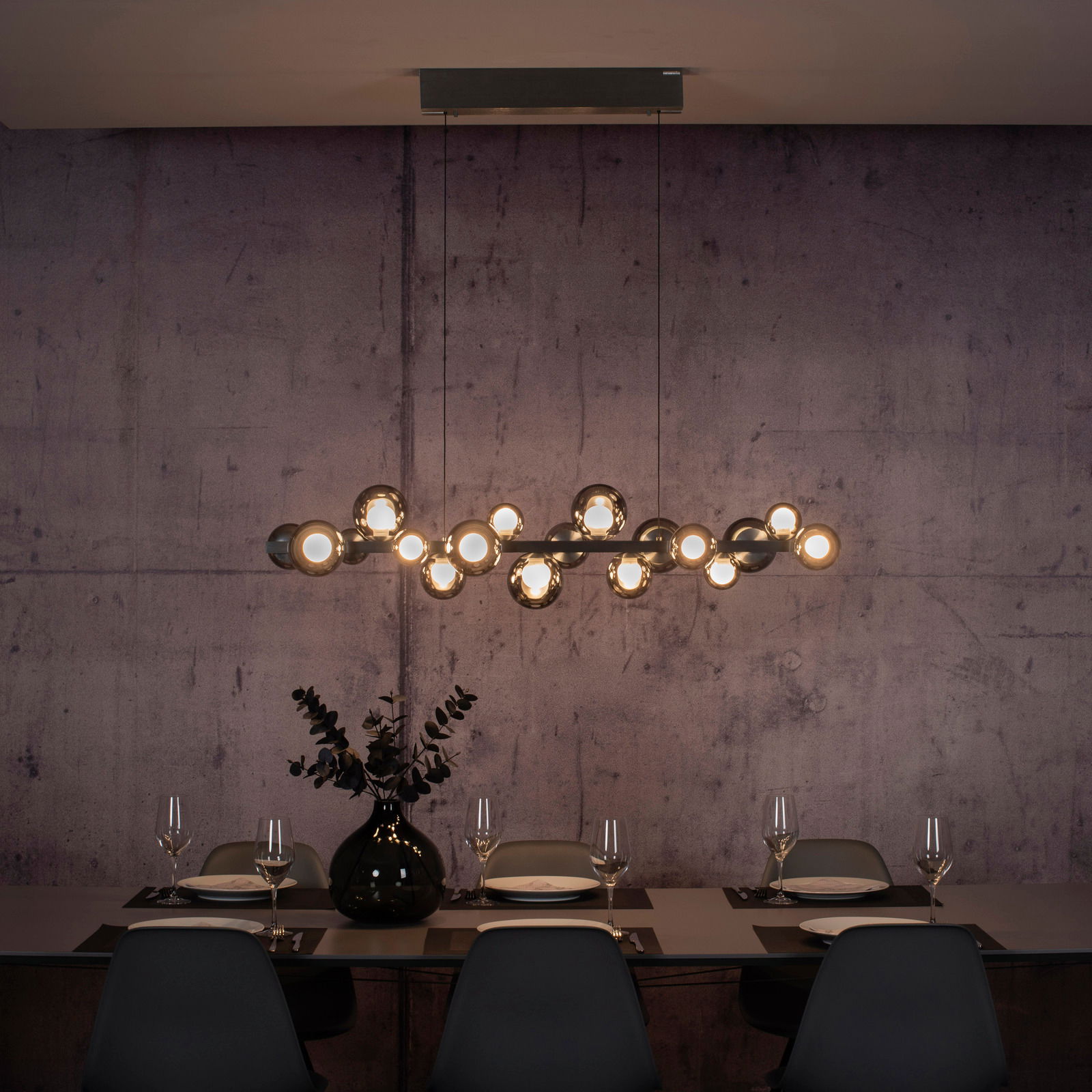 Moderne LED-Pendelleuchte über einem stilvoll gedeckten Esstisch, seitliche Perspektive