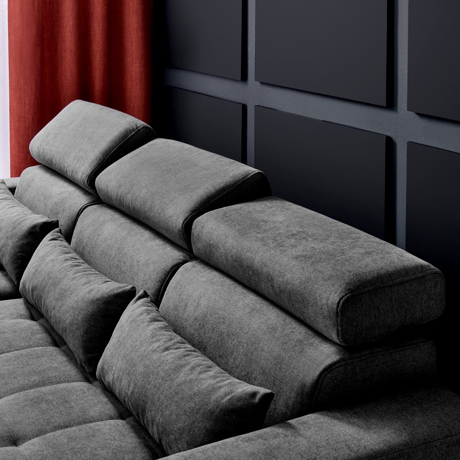 Graues Sofa mit verstellbaren Kopfstützen und Kissen, seitliche Perspektive