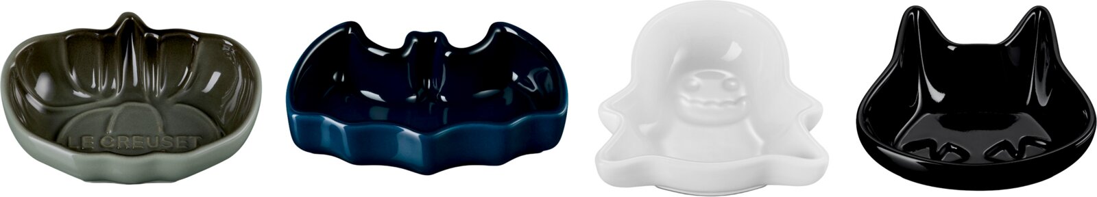 Vier glänzende Le Creuset Keramikschalen in Halloween-Formen – Kürbis, Fledermaus, Geist und Katze – in Grau, Dunkelblau, Weiß und Schwarz, frontal aus leicht erhöhter Perspektive