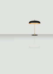 Moderne Tischleuchte mit schwarzem Schirm und goldener Stange, seitliche Perspektive