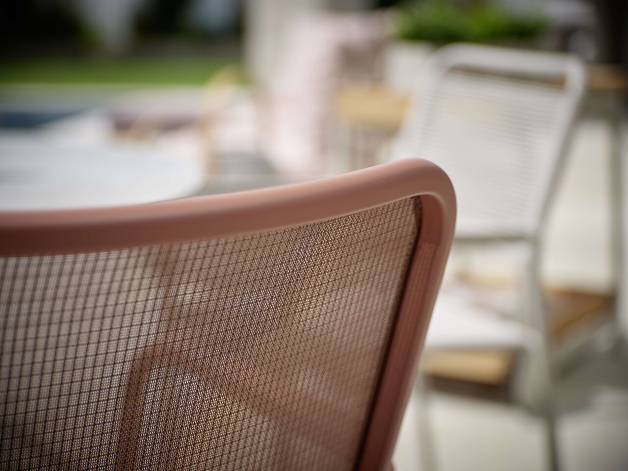 Nahaufnahme eines Stapelsessels mit braunem Netzrücken, seitliche Perspektive.