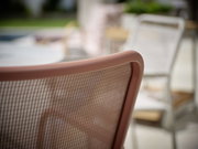 Nahaufnahme eines Stapelsessels mit braunem Netzrücken, seitliche Perspektive.