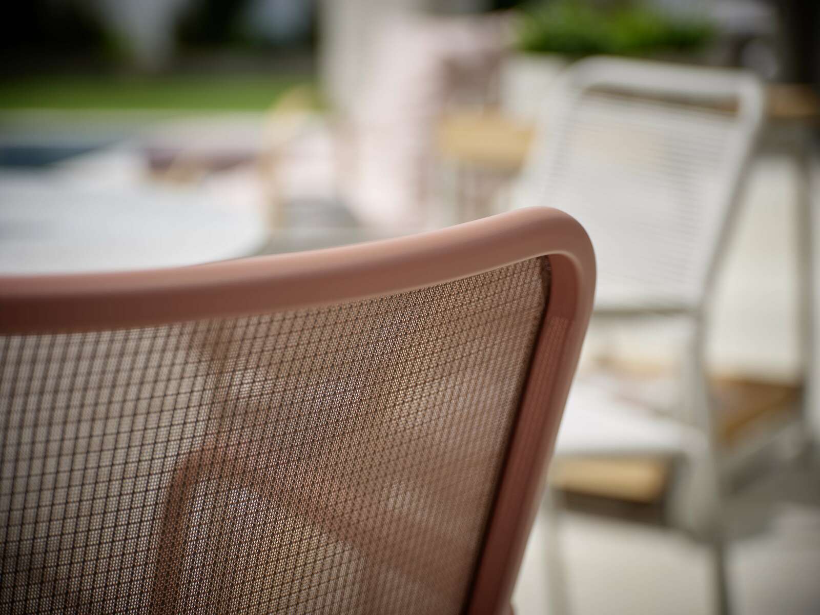 Nahaufnahme eines Stapelsessels mit braunem Netzrücken, seitliche Perspektive.