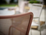 Nahaufnahme eines Stapelsessels mit braunem Netzrücken, seitliche Perspektive.