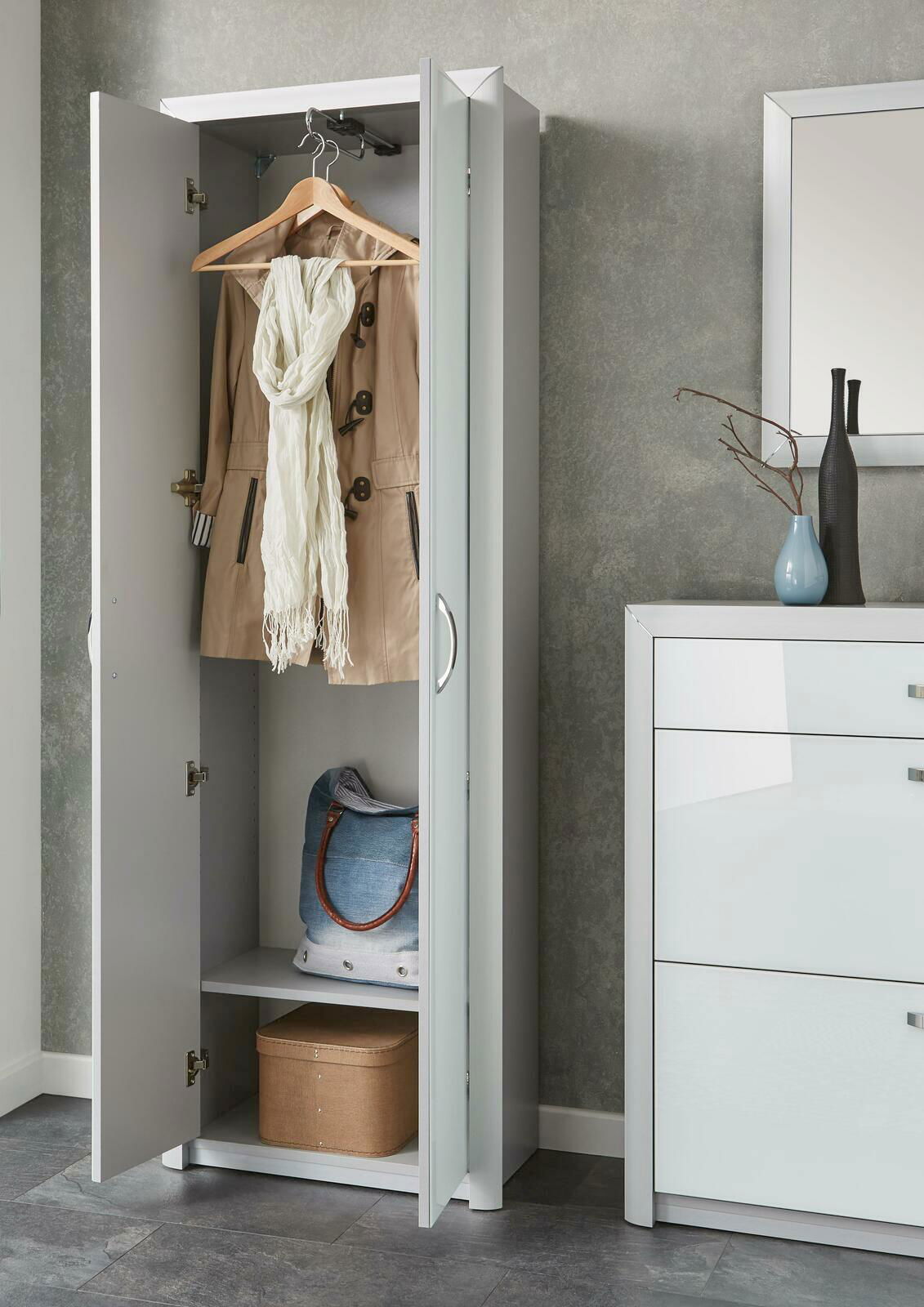 Moderner weißer Garderobenschrank mit geöffneter Tür, zeigt hängenden Mantel und Schal, sowie Ablagefächer mit Tasche und Box, seitliche Perspektive.