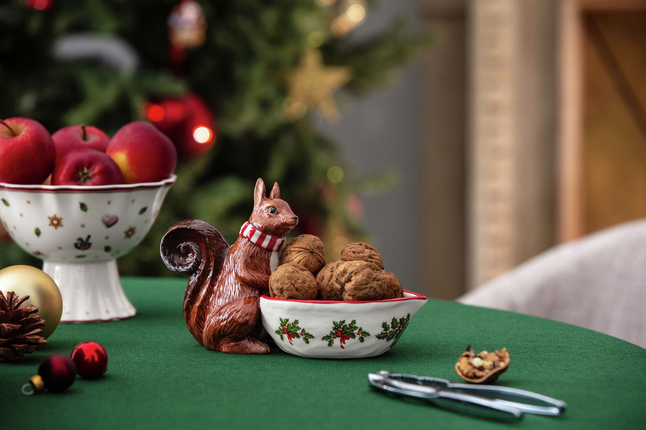 Villeroy & Boch Eichhörnchen- Schale Keramik-Eichhörnchen mit Schal hält eine Schale mit Walnüssen, auf einem festlich gedeckten Tisch mit Weihnachtsdekoration, seitliche Perspektive.