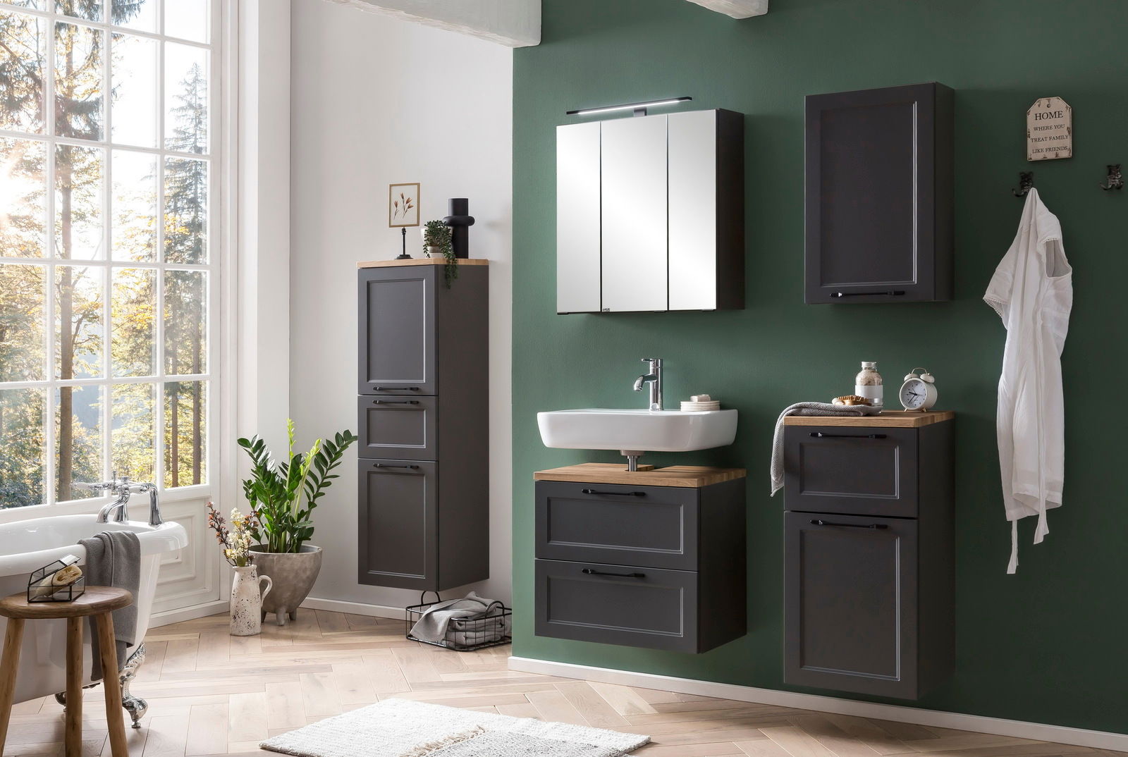 Moderner Spiegelschrank in einem stilvoll eingerichteten Badezimmer mit grüner Wand und natürlichem Licht von einem großen Fenster. Frontalansicht.