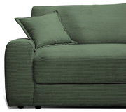 Grünes Big-Sofa mit geripptem Stoffbezug, seitliche Perspektive mit Kissen auf der linken Armlehne.