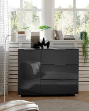 Moderne schwarze Kommode mit Hochglanzoberfläche, frontal fotografiert, dekoriert mit Pflanzen und Büchern vor einem Fenster.