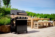 BBQ-Station Videro G4-S auf einer Terrasse, seitliche Perspektive mit Garten im Hintergrund