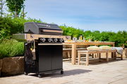 BBQ-Station Videro G4-S auf einer Terrasse, seitliche Perspektive mit Garten im Hintergrund