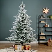 Künstlicher Weihnachtsbaum mit Schnee-Effekt, D.132 H.180 cm, frontal fotografiert, umgeben von Geschenken und weihnachtlicher Dekoration.