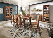 Esszimmer mit Holzmöbeln im rustikalen Stil, bestehend aus einem Esstisch, sechs Stühlen, einer Vitrine, einem Sideboard und einem Bücherregal. Die Perspektive zeigt den Raum von schräg vorne, mit einem Teppich auf dem Holzboden und großen Fenstern im Hin
