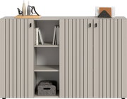 Modernes Sideboard in Hellgrau mit vertikaler Rillenoptik und schwarzen Griffen, mittigem offenen Regal mit Büchern und Stoffbox, dekoriert mit Vasen und Briefständer; Frontansicht.