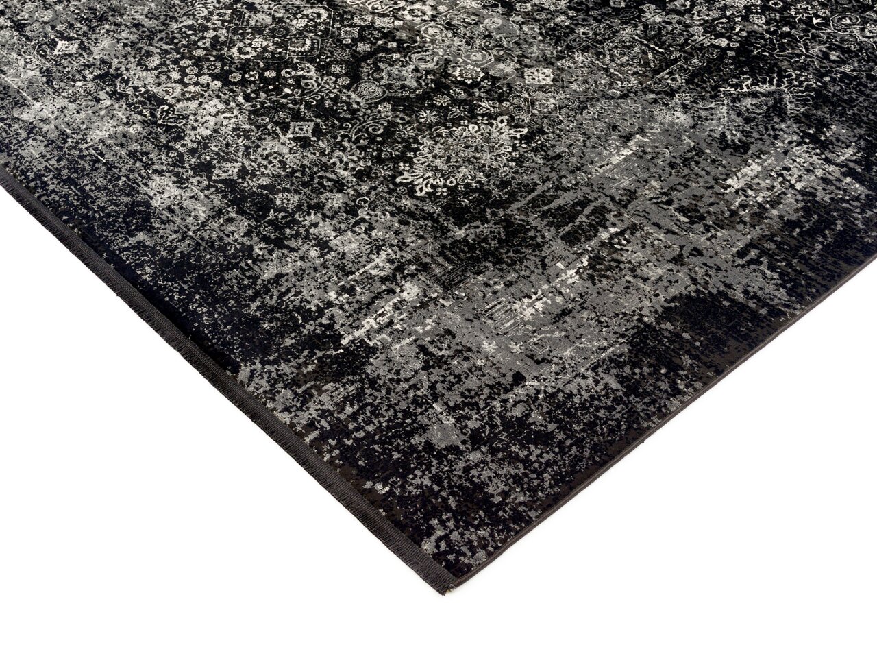 Designer Teppich in Schwarz und Grau mit komplexem Muster, perspektivisch von der Ecke aufgenommen