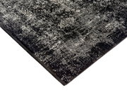 Designer Teppich in Schwarz und Grau mit komplexem Muster, perspektivisch von der Ecke aufgenommen