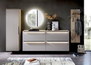 Moderne Garderoben-Kombination in heller Holzoptik, bestehend aus einem hohen Schrank, einer Kommode mit Schubladen und einem Wandpaneel mit Haken. Perspektive: Frontalansicht.