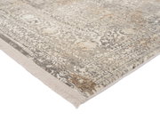 Nahaufnahme eines Designer-Teppichs mit detailliertem Muster in Beige- und Grautönen, perspektivisch von der Ecke aufgenommen.