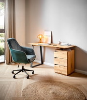 Moderner Schreibtisch aus Holz mit schwarzem Metallgestell, seitlich von einem grünen Bürostuhl und einer kleinen Lampe auf der Tischplatte begleitet, aus seitlicher Perspektive fotografiert.