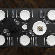 Elegant dinerbord NewMoon 27 cm wit, van bovenaf gefotografeerd op een stijlvol gedekte tafel met bestek en glazen.