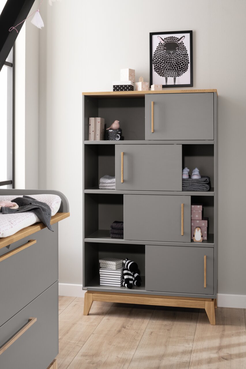 Paidi Regal STEN Graues Regal mit Holzakzenten, dekoriert mit Spielzeug und Boxen, aus frontaler Perspektive.
