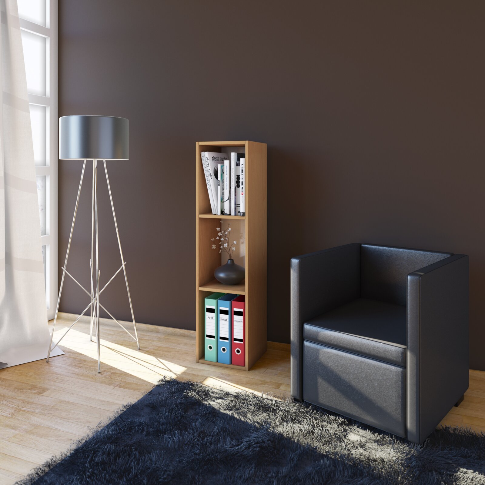 Schmales, hohes Holzregal mit drei Fächern, bestückt mit Büchern, Vase und farbigen Ordnern, in moderner Wohnzimmerecke neben Stehlampe und schwarzem Sessel Frontansicht in leichter Seitenperspektive von links.