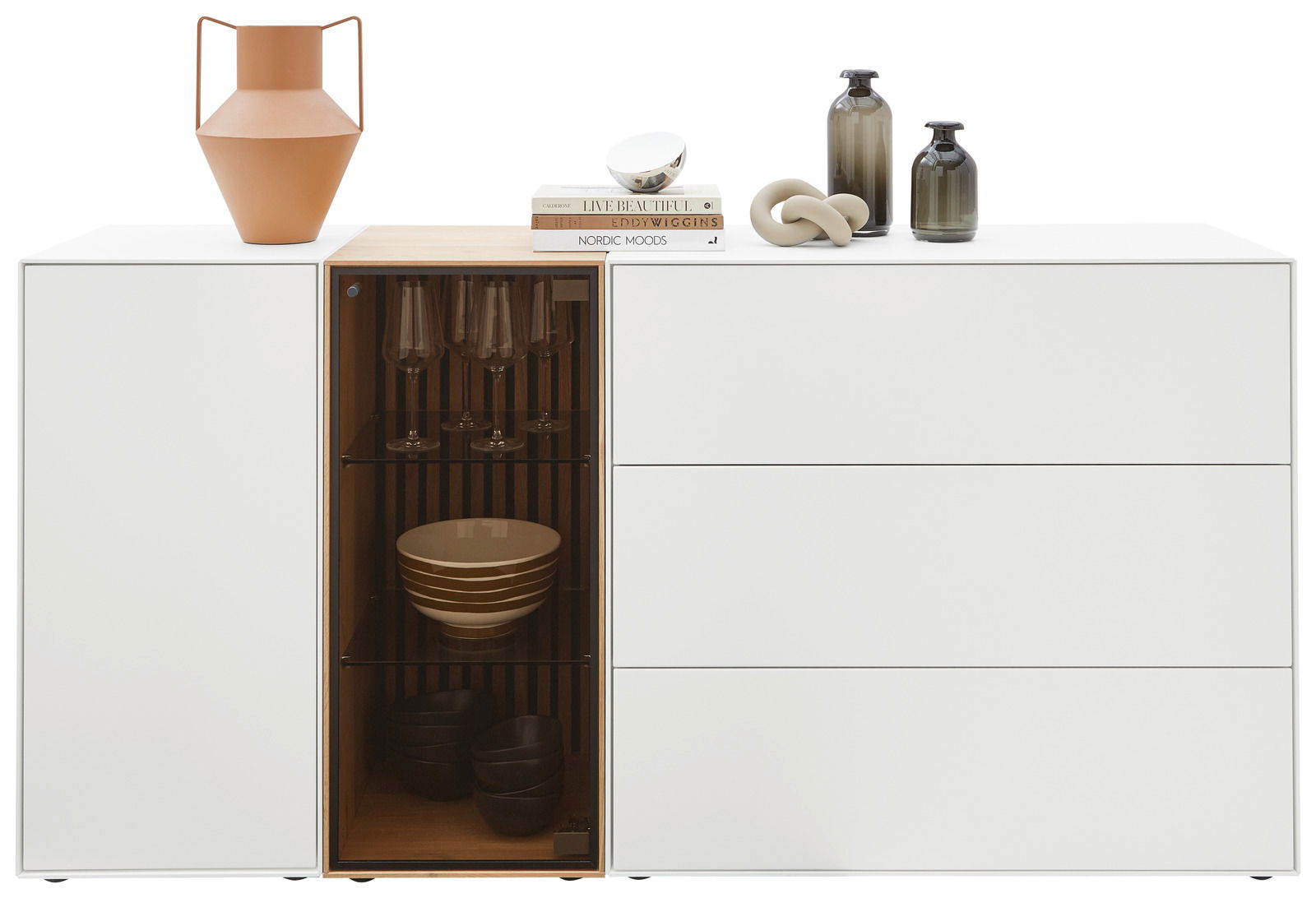 Modernes weißes Sideboard mit Glasvitrine, dekoriert mit Vasen und Büchern, Frontalansicht.