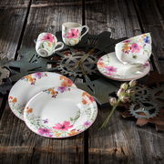 Vogelperspektive auf ein 8-teiliges Starter-Set Mariefleur mit floralem Design auf rustikalem Holztisch, bestehend aus Tellern, Tassen und Schalen.