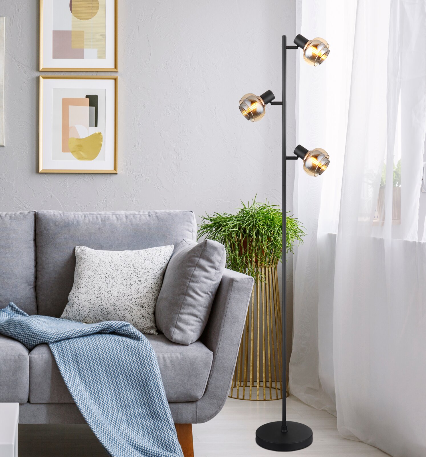 Moderne Stehleuchte mit drei kugelförmigen Lampenschirmen in einem stilvollen Wohnzimmer, seitliche Perspektive.