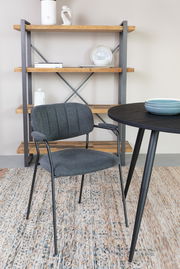 Moderner grauer Stuhl mit Metallbeinen, seitliche Perspektive, vor einem Tisch und einem Regal im Hintergrund.