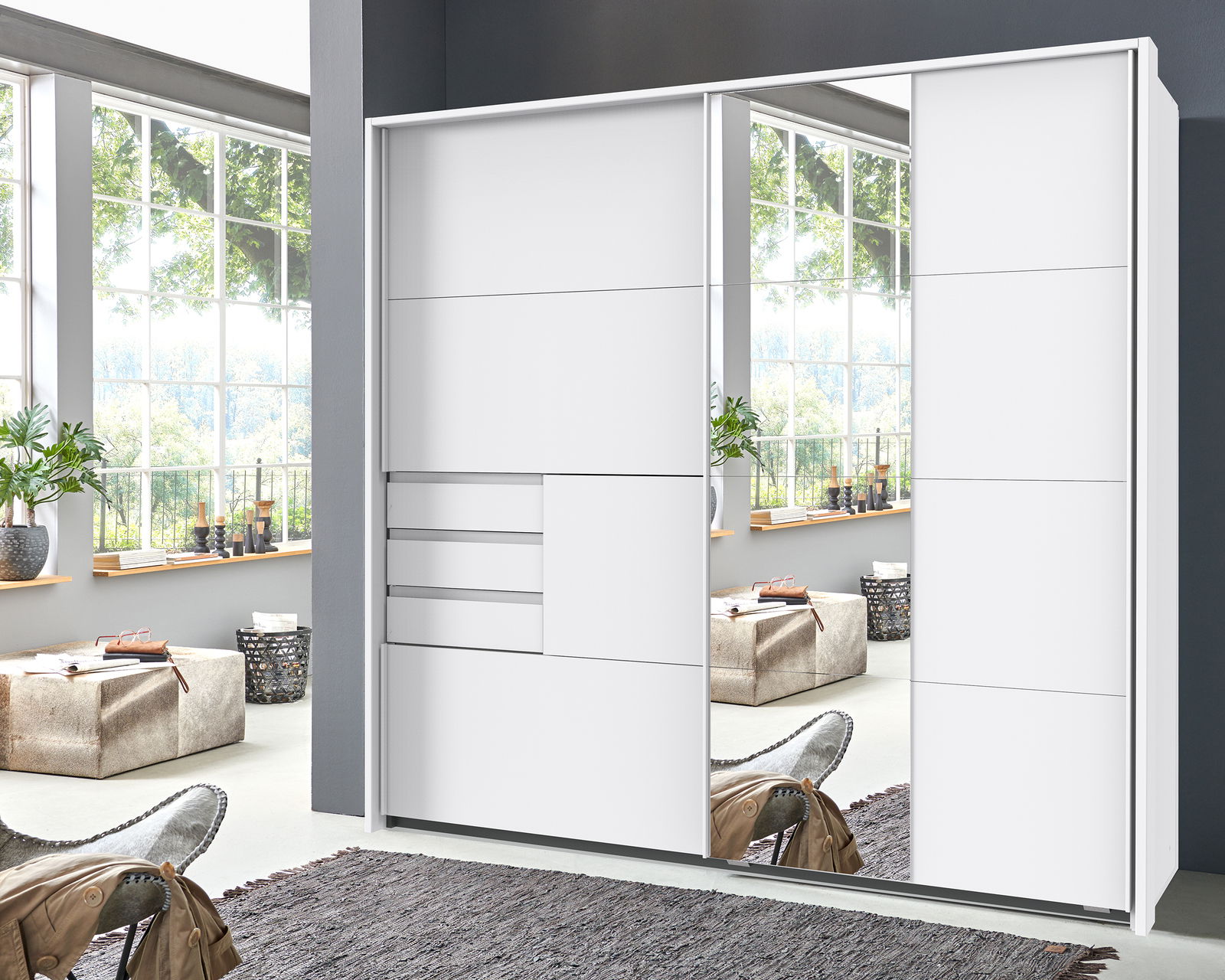 Moderner weißer Schwebetürenschrank mit Spiegel, frontale Ansicht in einem hellen Raum mit großen Fenstern.