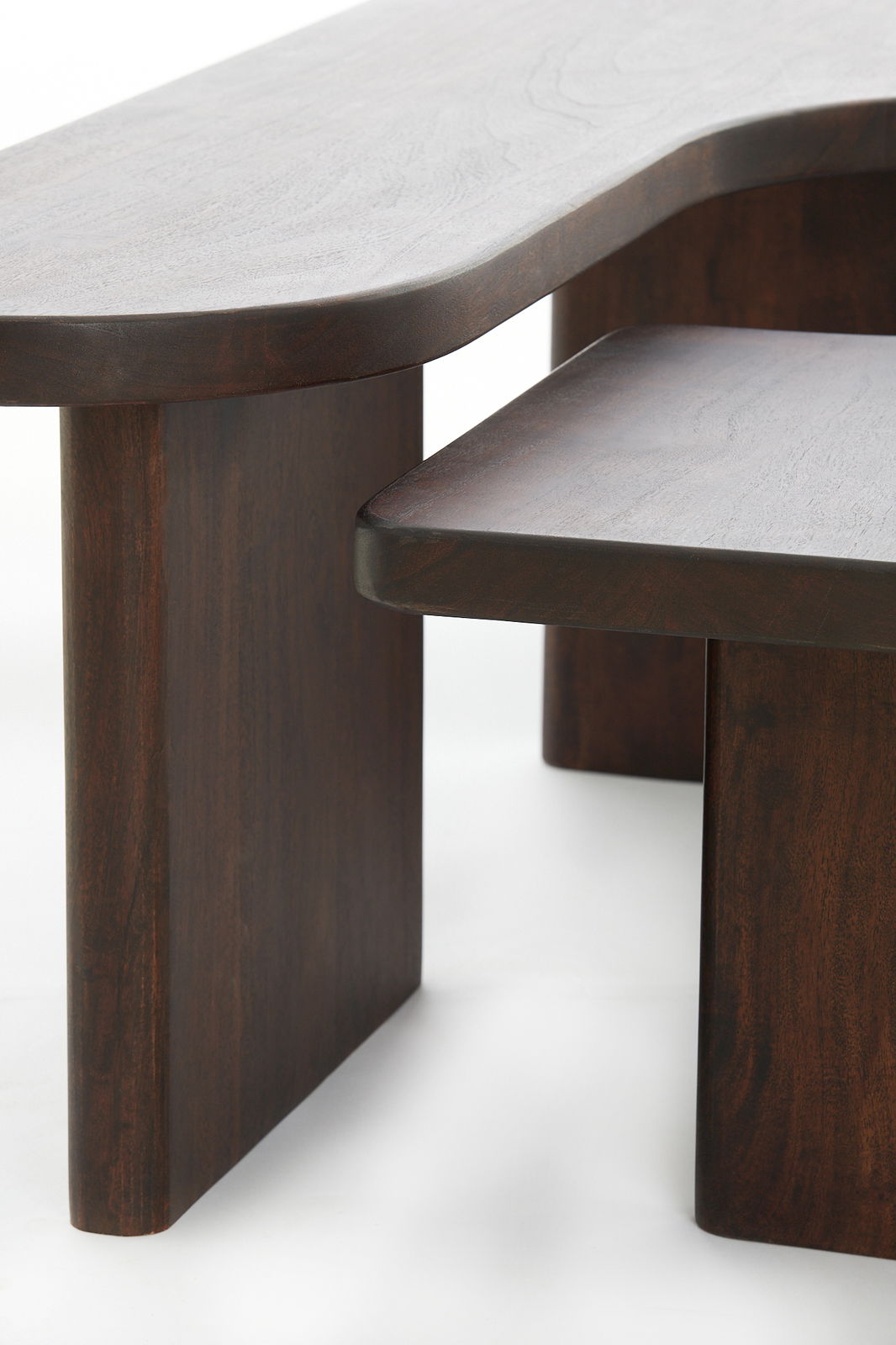 Nahaufnahme eines modernen Couchtisches aus dunklem Holz mit abgerundeten Kanten, seitliche Perspektive.