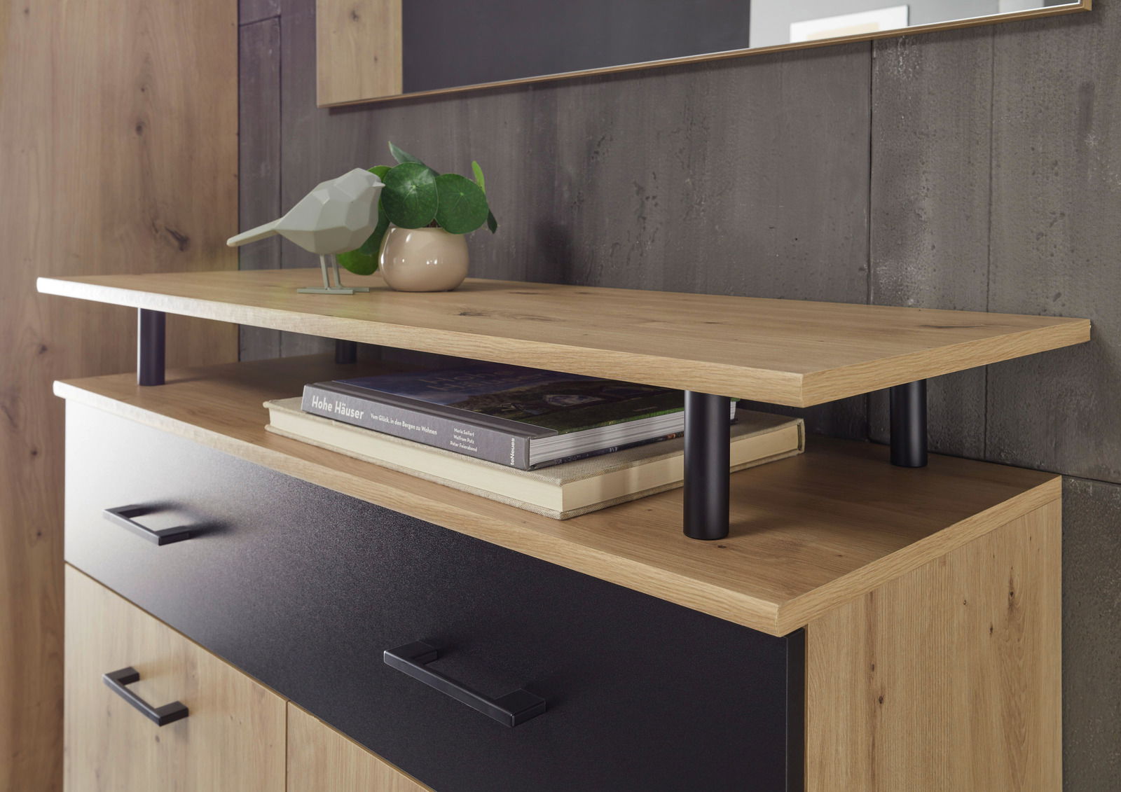 Nahaufnahme eines modernen Garderoben-Sets mit Holz- und Metallelementen, dekoriert mit einem Buch, einer Pflanze und einer Vogelstatue, seitliche Perspektive.