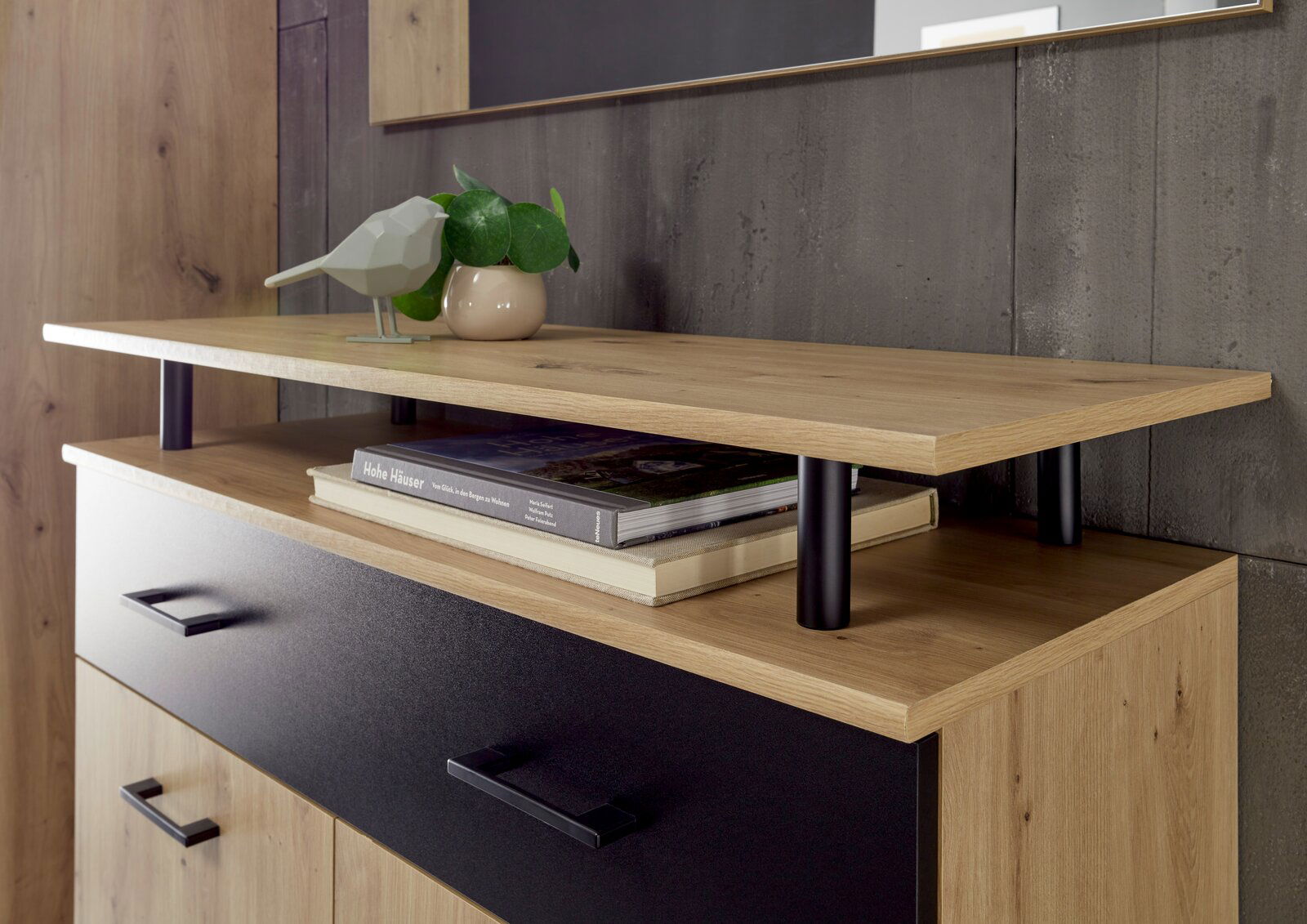 Nahaufnahme eines modernen Garderoben-Sets mit Holz- und Metallelementen, dekoriert mit einem Buch, einer Pflanze und einer Vogelstatue, seitliche Perspektive.