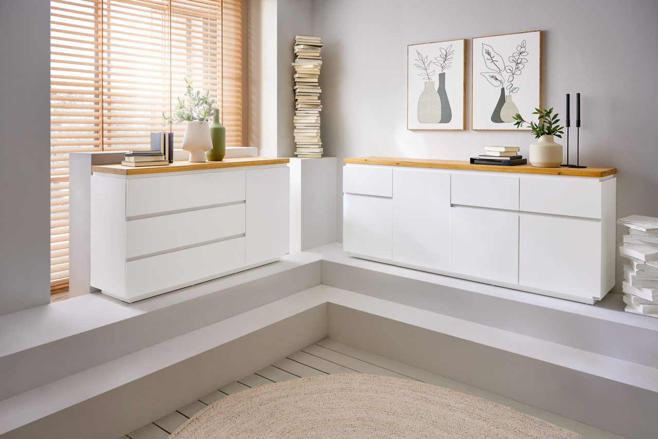 Zwei moderne, weiße Sideboards mit Holzoberfläche in einem hellen Raum, seitliche Perspektive.
