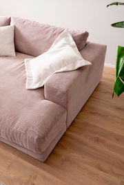 Nahaufnahme eines kleinen Megasofas in rosa Cordstoff mit weißen Kissen, von schräg oben fotografiert.