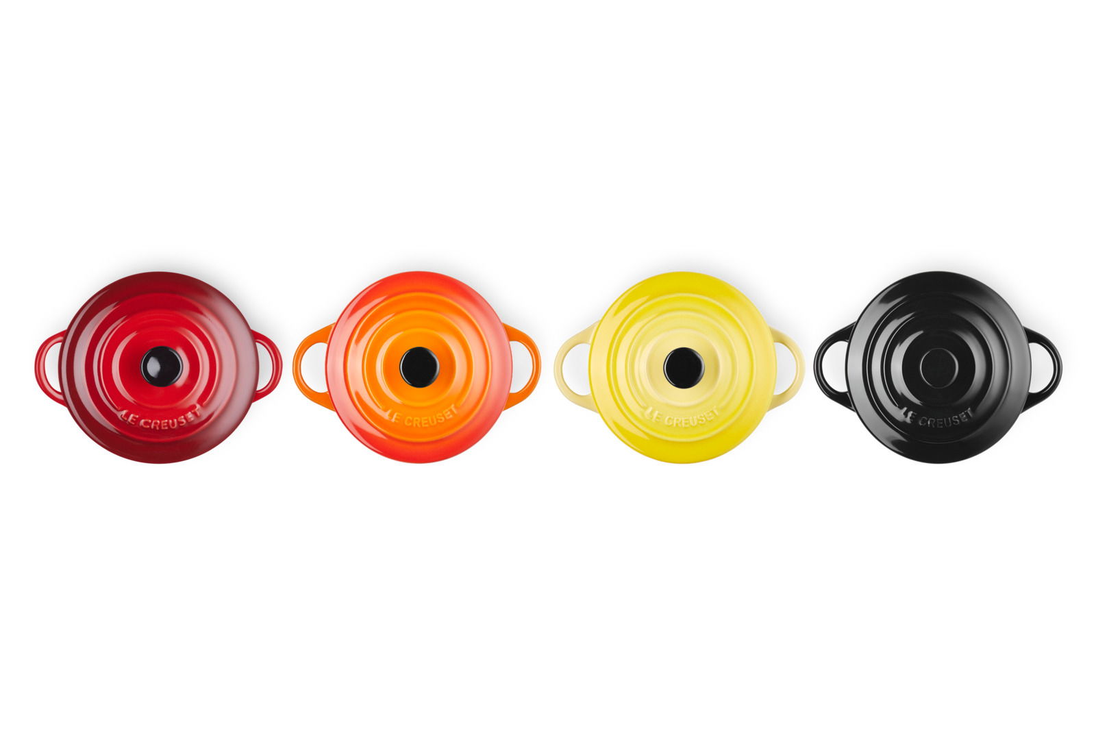 Vier Mini-Cocottes in verschiedenen Farben (Rot, Orange, Gelb, Schwarz) aus der Vogelperspektive.