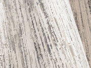 Nahaufnahme eines Designer-Teppichs mit abstraktem Muster in Grau- und Beigetönen, seitliche Perspektive