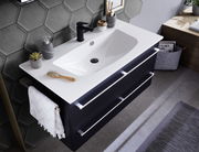 Moderne Badkombination mit weißem Waschbecken und schwarzem Unterschrank, von oben fotografiert. Dekoriert mit Seifenspender, Pflanze und Handtuch.