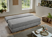 Graues Funktionssofa in flacher Position, seitliche Perspektive, in modernem Wohnzimmer mit Pflanzen und Dekoration.
