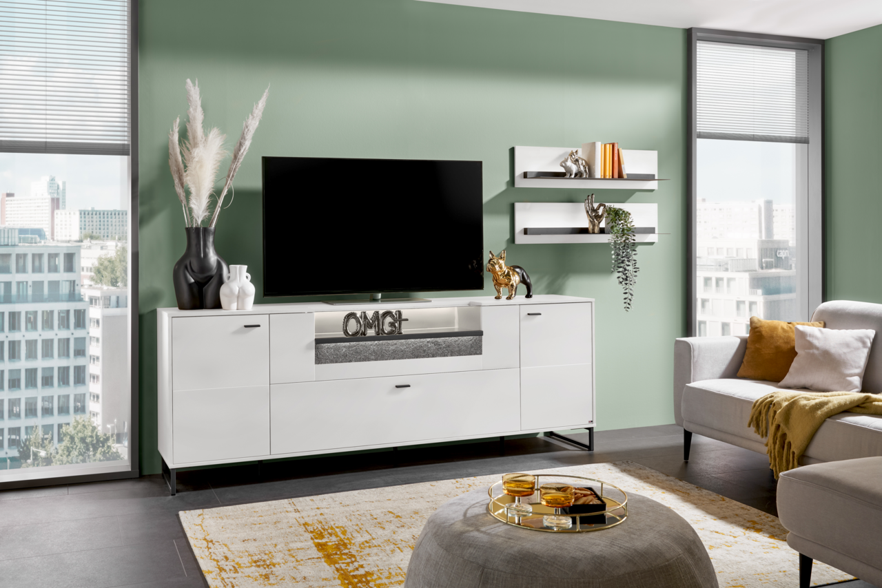 Modernes weißes TV-Lowboard in einem stilvollen Wohnzimmer, frontal betrachtet, mit Dekorationen und einem großen Fernseher darauf.