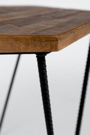 Nahaufnahme eines Beistelltisches mit einer rustikalen Holzplatte und schwarzen Metallbeinen, seitliche Perspektive.