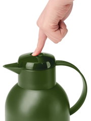 Groene thermoskan SAMBA 1,5 l, gezien van bovenaf, met een hand die op de knop van het deksel drukt.